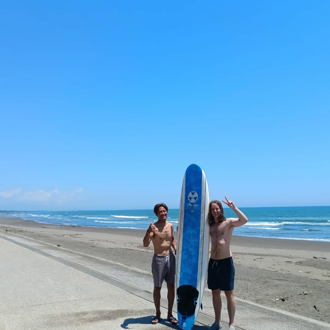 Ken avec un voyageur et une planche de surf sur la plage